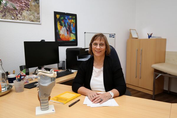 Speech therapist Cordula Hutzler sits at her desk in her treatment room