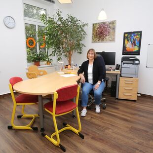 Treatment room with table and chairs and a computer workstation where Mrs Hutzler, the speech therapist, is sitting.